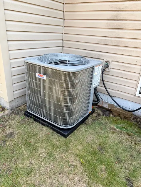 Air conditioning unit with piping next to a house in Maple Grove