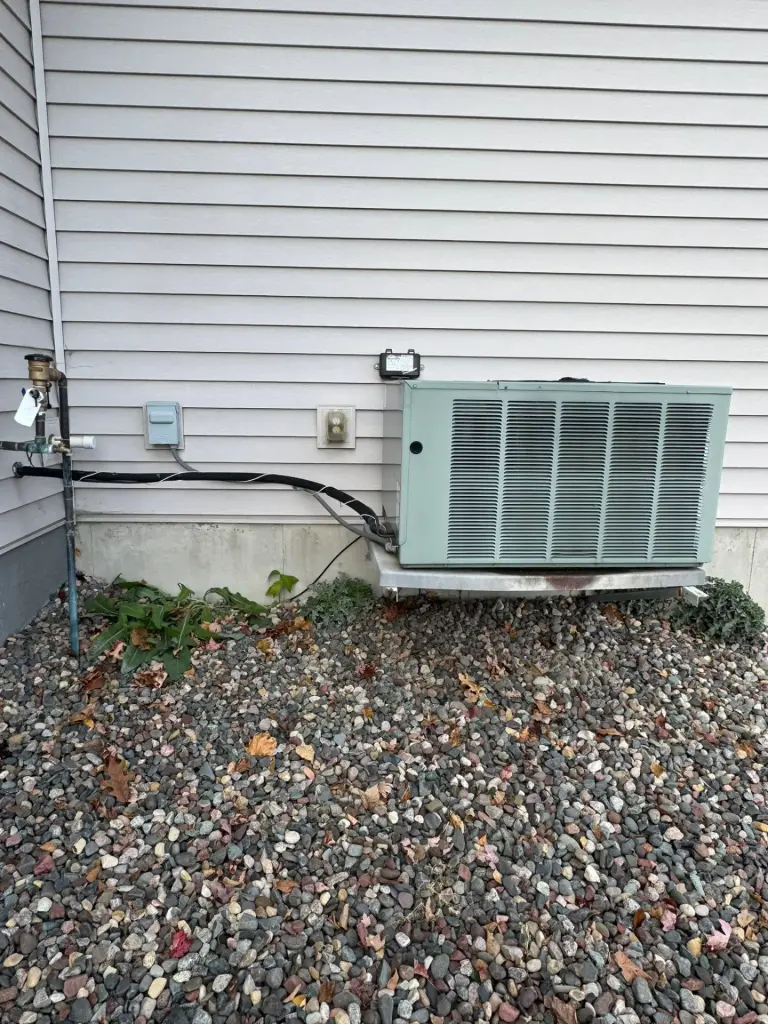Outdoor AC unit on a gravel bed along a home's siding